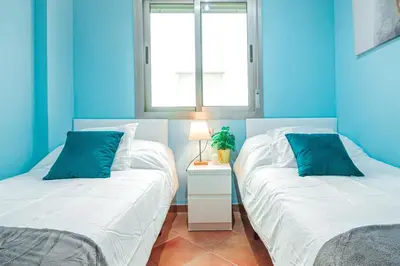 two beds in a room with blue walls at Edomus Playa de la Costilla in Rota