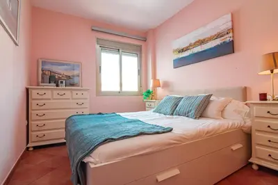 a bedroom with pink walls and a bed and a window at Edomus Playa de la Costilla in Rota