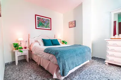 a bedroom with a large bed with blue pillows at Edomus Faro de Rota in Rota