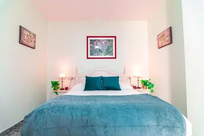 a bedroom with a large bed with blue pillows at Edomus Faro de Rota in Rota