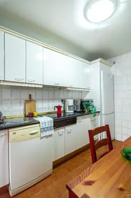 a kitchen with white cabinets and a wooden table at Edomus Faro de Rota in Rota