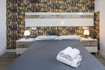 a bedroom with a bed with towels and a wallpaper at La Terraza by Staycare in Rota