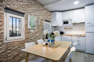 a kitchen with a wooden table and white cabinets at La Terraza by Staycare in Rota
