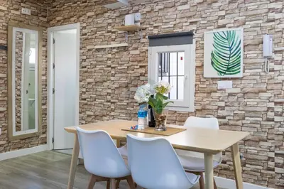 a dining room with a wooden table and white chairs at La Terraza by Staycare in Rota