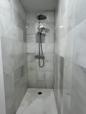 a white bathroom with a shower with a shower head at Brand new apartment in the heart of Jerez! in Jerez de la Frontera