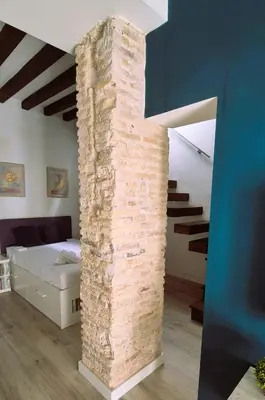 a brick wall in a bedroom with a bed and stairs at Ático de Goleta by Gades Gestión in Cádiz