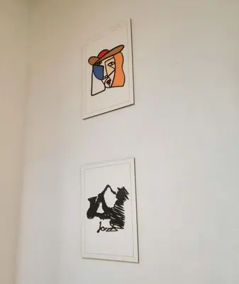 two pieces of art hanging on a white wall at Ático de Goleta by Gades Gestión in Cádiz