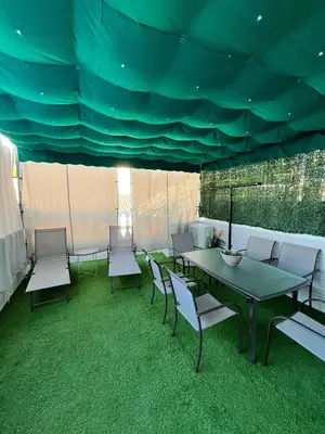 a patio with a table and chairs and green carpet at Tu ático ideal Terraza, Centro y Playa a pie in Sanlúcar de Barrameda