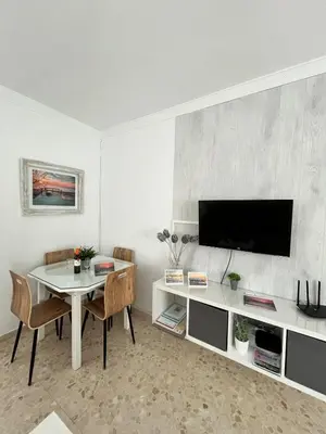 a living room with a table and a tv at Tu ático ideal Terraza, Centro y Playa a pie in Sanlúcar de Barrameda