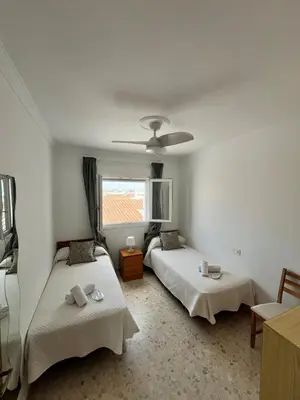 a bedroom with two beds and a window at Tu ático ideal Terraza, Centro y Playa a pie in Sanlúcar de Barrameda