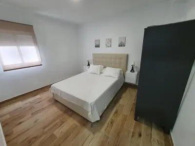 a white bedroom with a bed and a window at Fabuloso Apartamento centrico San Miguel WIFI in Jerez de la Frontera