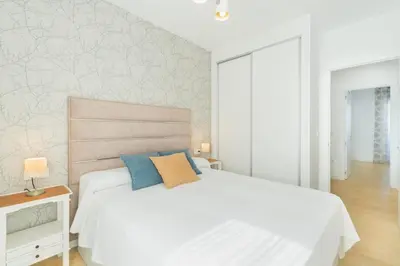 a bedroom with a white bed with blue pillows at Lujoso chalet con jardín privado a 300 metros de la playa in Conil de la Frontera