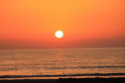 an orange sunset over the ocean with a beach at Apartamento Del Rio Playa in Cádiz