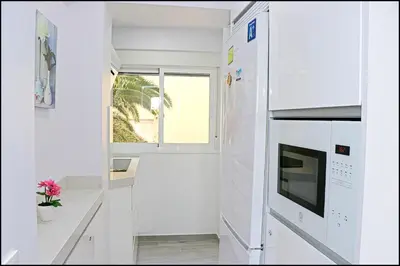 a kitchen with white cabinets and a window at Apartamento Del Rio Playa in Cádiz