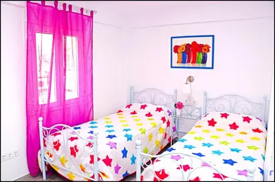 a bedroom with a bed and a window with pink curtains at Apartamento Del Rio Playa in Cádiz