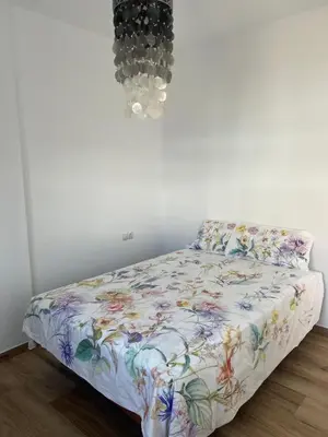 a bedroom with a bed with a floral comforter at Chalet Familiar NUEVO-10min Cádiz Capital in Puerto Real