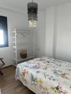 a bedroom with a bed and a chandelier at Chalet Familiar NUEVO-10min Cádiz Capital in Puerto Real