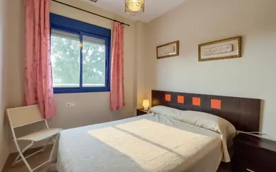 a bedroom with a bed and a window and a chair at Family Oasis in Chipiona - Pool - Terrace - Padel in Cádiz