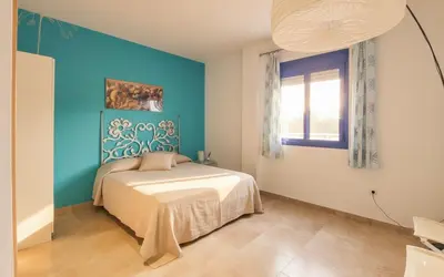 a bedroom with a bed and a blue wall at Family Oasis in Chipiona - Pool - Terrace - Padel in Cádiz