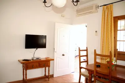 a room with a television and a table and a door at Studio Sleeps 4 with Terrace in Chipiona