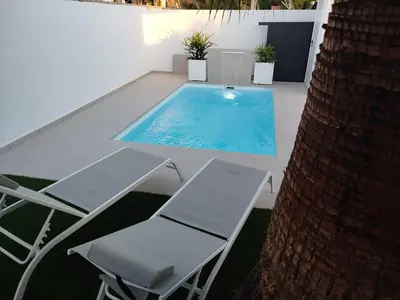 a swimming pool with two chairs and a table at Pacifico conil in Cádiz