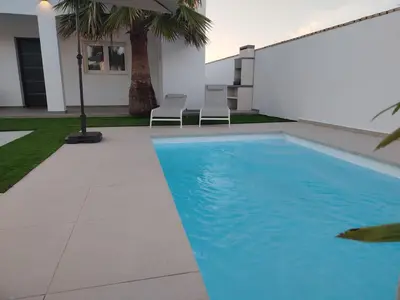 a swimming pool with chairs next to a house at Pacifico conil in Cádiz