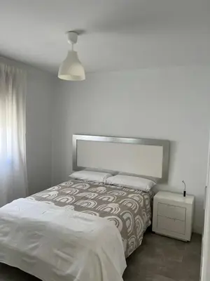 a white bedroom with a bed and a lamp at Casa Flamenco in El Cuervo