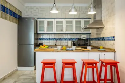 a kitchen with four red stools in front of a counter at Grand Marina Suite - Puerto Sherry in El Puerto de Santa María