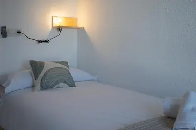 a bedroom with a white bed with a light on it at Casa Salmedina in Sanlúcar de Barrameda