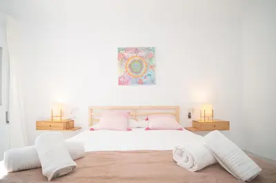 a bedroom with a large white bed with two lamps at Casa Salmedina in Sanlúcar de Barrameda