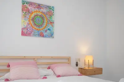 a bed with two pink pillows and a painting on the wall at Casa Salmedina in Sanlúcar de Barrameda