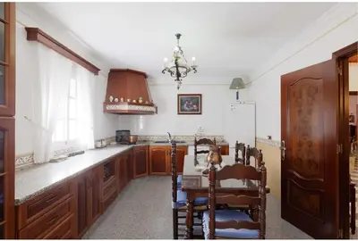 a kitchen with wooden cabinets and a table and a chandelier at Casa Palacete en el corazón de Cádiz in Paterna de Rivera