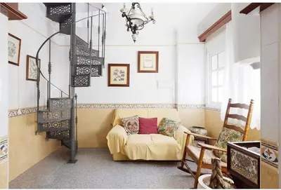 a living room with a yellow couch and a staircase at Casa Palacete en el corazón de Cádiz in Paterna de Rivera
