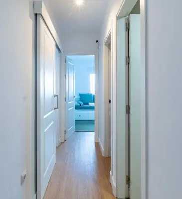 a hallway with white doors and wooden floors at Doñana Loft 17 in Sanlúcar de Barrameda