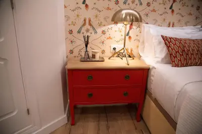 a red dresser with a lamp on it next to a bed at Hidden Gem GRAN TEATRO FALLA SUITES by ApartmentsinCadiz in Cádiz