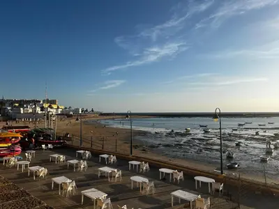 a group of white tables and chairs on a beach at Hidden Gem GRAN TEATRO FALLA SUITES by ApartmentsinCadiz in Cádiz