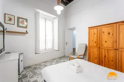 a bedroom with a white bed and a chair at Adolfo de Castro by Cadiz Time in Cádiz