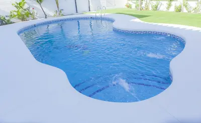 a swimming pool in a house with blue water at Hotel Novomar in Chiclana de la Frontera