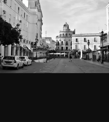 a black and white photo of a city street with cars at plaza esteve in Jerez de la Frontera