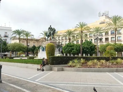 a man walking past a statue in front of a building at plaza esteve in Jerez de la Frontera