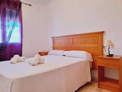 a bedroom with two beds with white sheets and a window at Apartamentos Turísticos Taymar in Chiclana de la Frontera
