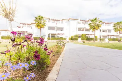 a walkway in front of a white building with flowers at Apartamentos Turísticos Taymar in Chiclana de la Frontera