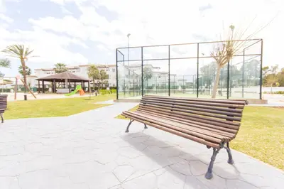 a bench in a park with a building in the background at Apartamentos Turísticos Taymar in Chiclana de la Frontera