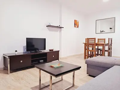 a living room with a couch and a tv and a table at Apartamentos Turísticos Taymar in Chiclana de la Frontera