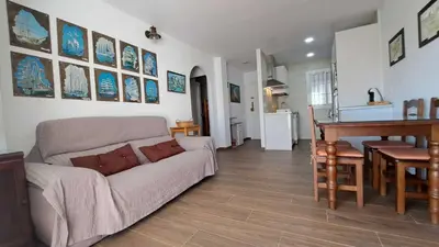 a living room with a couch and a table and a kitchen at Apartamento en primera linea de playa in Novo Sancti Petri
