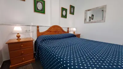 a bedroom with a blue bed and a dresser and a mirror at Apartamento en primera linea de playa in Novo Sancti Petri