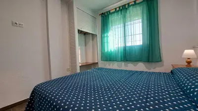a bedroom with a blue bed and a window at Apartamento en primera linea de playa in Novo Sancti Petri