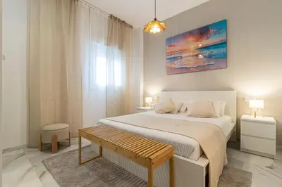 a white bedroom with a bed and a bench at Jerez Boutique by Sanz in Jerez de la Frontera
