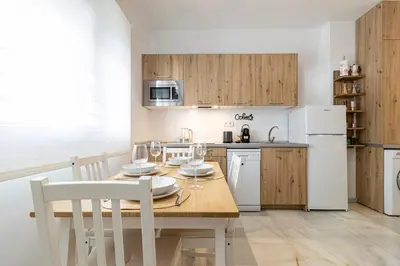 a kitchen with a wooden table and a white refrigerator at Jerez Boutique by Sanz in Jerez de la Frontera