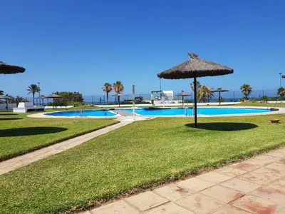 a resort with an umbrella and a swimming pool at Apartamento en primera línea de playa en 2ª planta in Novo Sancti Petri